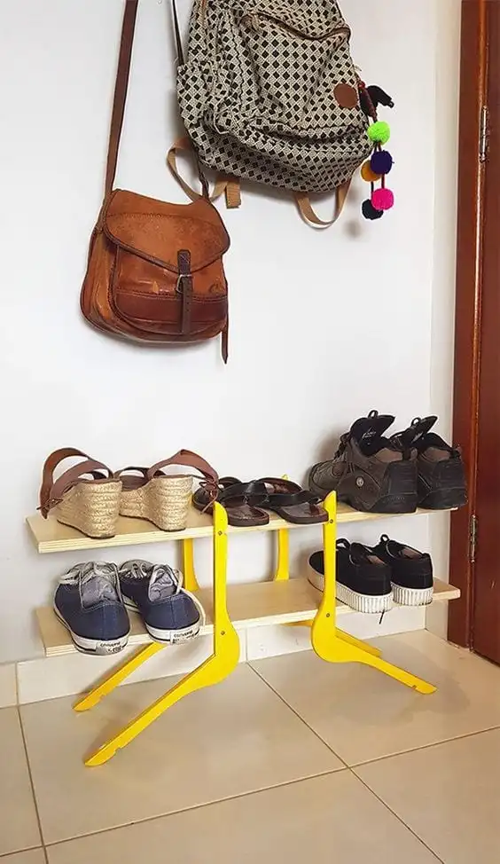 Les deux tablettes en bois sont pris en charge par le support. Pour eux, sont disposées cinq paires de chaussures. Au-dessus de la chaussure rack, il y a deux sacs suspendus. 